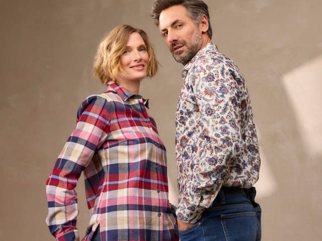 Zwei Personen tragen gemusterte Hemden – eine im karierter Stil, die andere mit floralem Muster. Beide Outfits wirken lässig, farbenfroh und modern kombiniert.