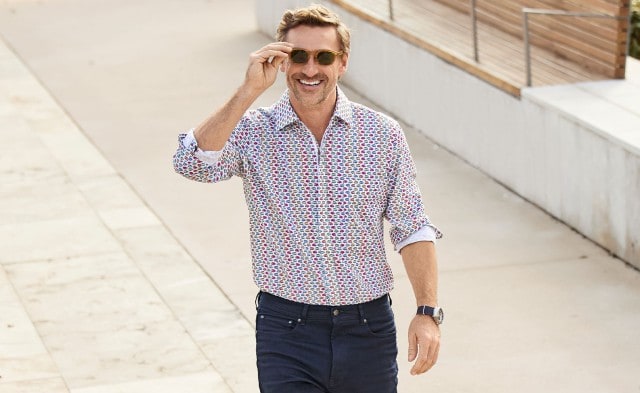 Mann gut gelaunt mit Sonnenbrille und Musterhemd.