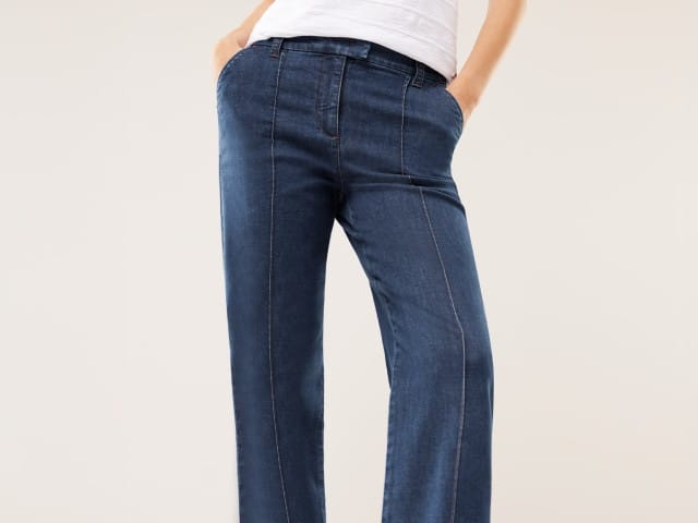 Eine Person trägt eine dunkelblaue Jeans mit geradem Schnitt und sichtbarer Mittelnaht. Der Stil wirkt zeitlos und lässig, kombiniert mit einem einfachen weißen Oberteil.