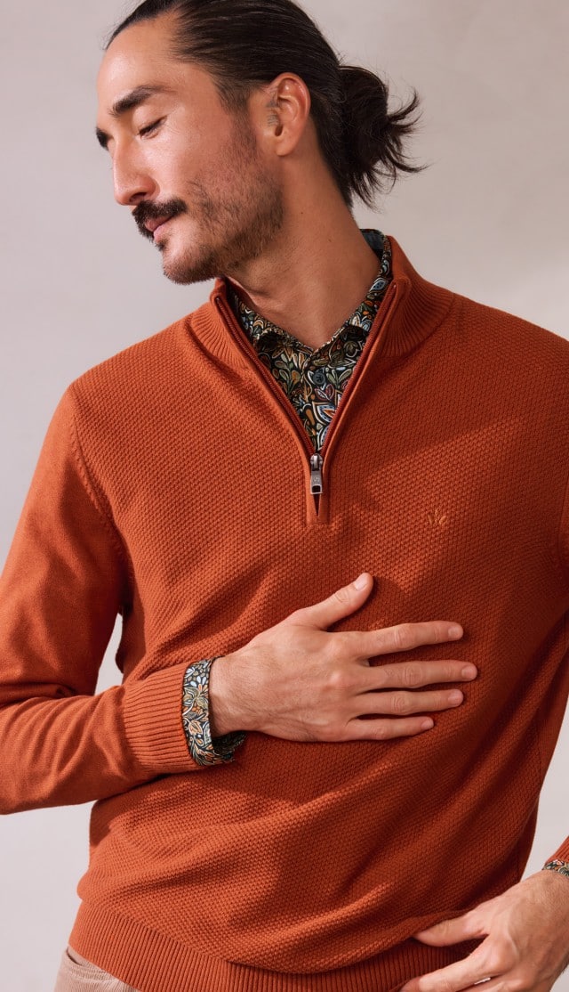 Ein Mann trägt einen Struktur-Troyer Herbstlaub in der Farbe Terra, darunter ein gemustertes Hemd.