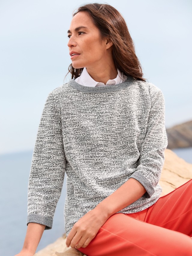 Frau sitzend an der Küste in Boucle-Sweaty und roter Culotte