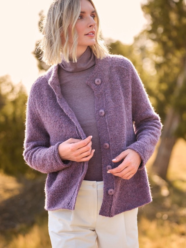 Eine Person trägt eine flauschige, lilafarbene Strickjacke über einem passenden Rollkragenpullover. Der Look wirkt weich, gemütlich und elegant zugleich.