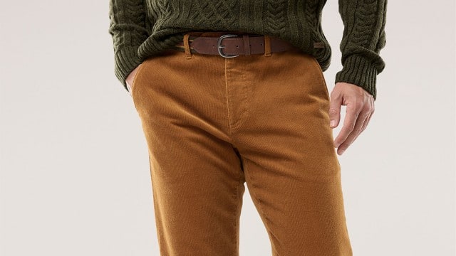 Eine Person trägt eine senffarbene Cordhose mit braunem Gürtel und einen dunkelgrünen Strickpullover. Der Stil wirkt herbstlich, warm und lässig. Eine Person trägt eine senffarbene Cordhose mit braunem Gürtel und einen dunkelgrünen Strickpullover. Der Stil wirkt herbstlich, warm und lässig.