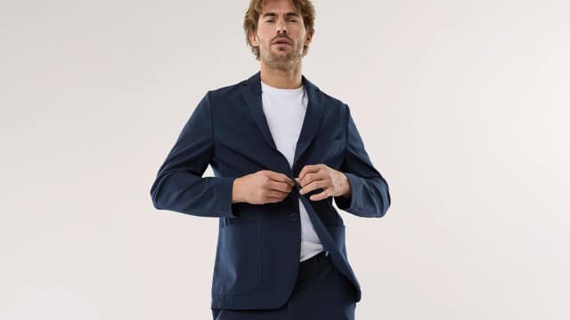 Ein Mann trägt einen dunkelblauen, lässig‑eleganten Anzug über einem weißen Shirt, was einen modernen, klaren und selbstbewusst entspannten Eindruck vermittelt.