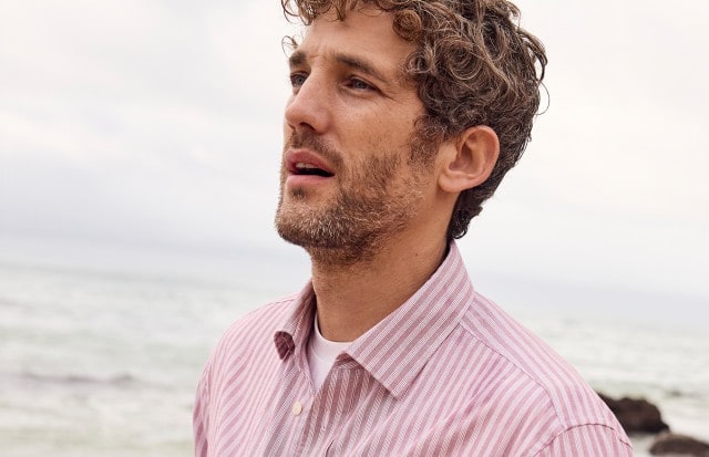 Ein Mann am Strand, trägt ein gestreiftes Hemd in Rot.