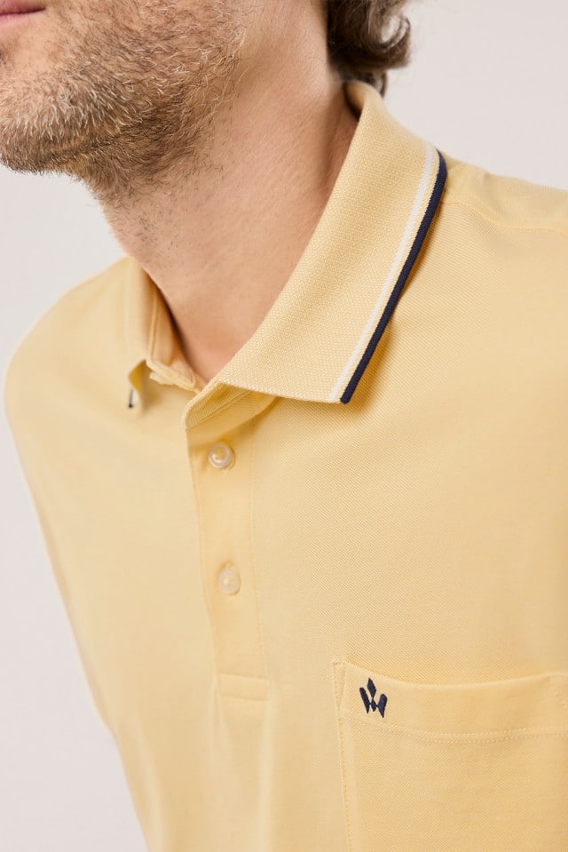 Ein Mann trägt ein Extraglatt-Polo Bicolor in Uni Gelb.