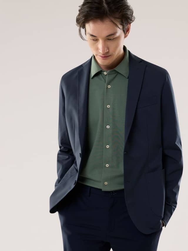 Ein Mann trägt einen dunkelblauen, klar geschnittenen Anzug über einem dezent grünen Hemd, wodurch das Outfit modern, ausgewogen und angenehm ruhig wirkt.