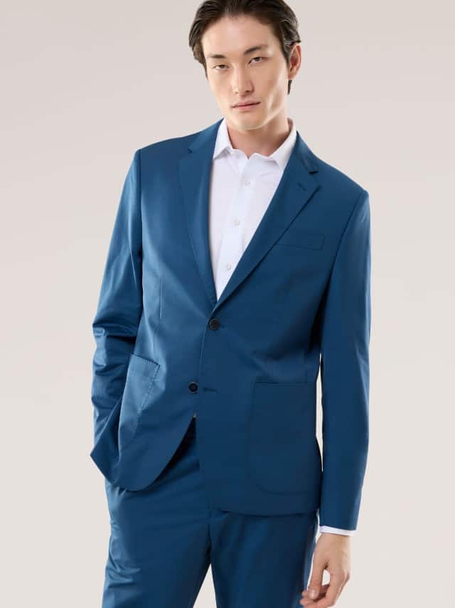 Ein Mann trägt einen modernen blau­farbenen Anzug mit weißem Hemd, was einen klaren, frischen und elegant‑ruhigen Eindruck vermittelt.
