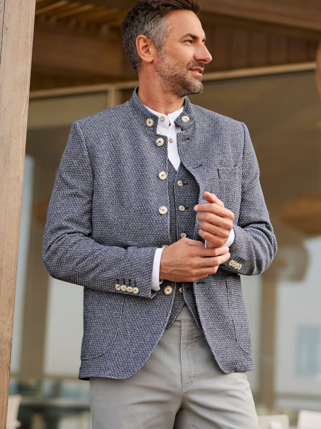 Ein Mann trägt eine blaue Strukturjacke mit passender Weste, was modern, klassisch und entspannt wirkt.