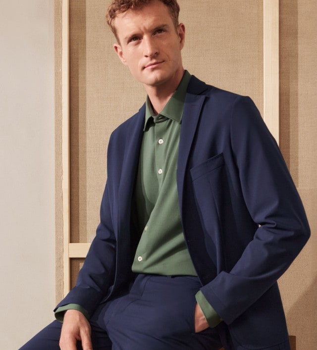 Ein Mann trägt einen dunkelblauen Anzug mit einem grünen Hemd. Der Look wirkt modern und elegant zugleich.