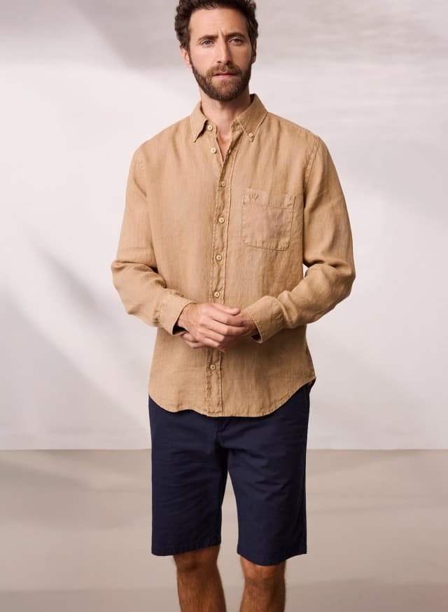 Ein Mann trägt ein Pures Leinen Hemd Überfärber in der Farbe Latte, dazu eine Bermudas. Ein Mann trägt ein Pures Leinen Hemd Überfärber in der Farbe Latte, dazu eine Bermudas.