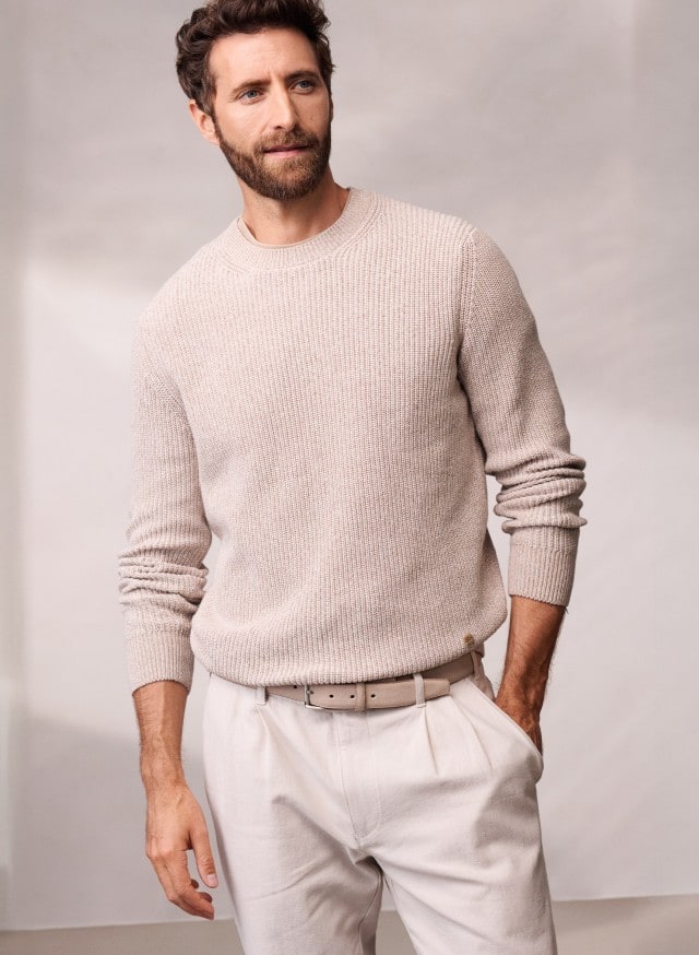 Ein Mann trägt einen Mouline Pullover in der Farbe Sand, dazu eine helle Chino. Ein Mann trägt einen Mouline Pullover in der Farbe Sand, dazu eine helle Chino.