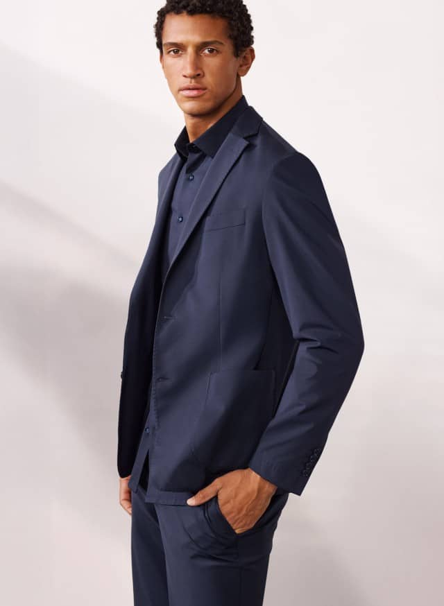 Ein Mann trägt einen Travel Anzug in Marine mit passendem Hemd. Ein Mann trägt einen Travel Anzug in Marine mit passendem Hemd.