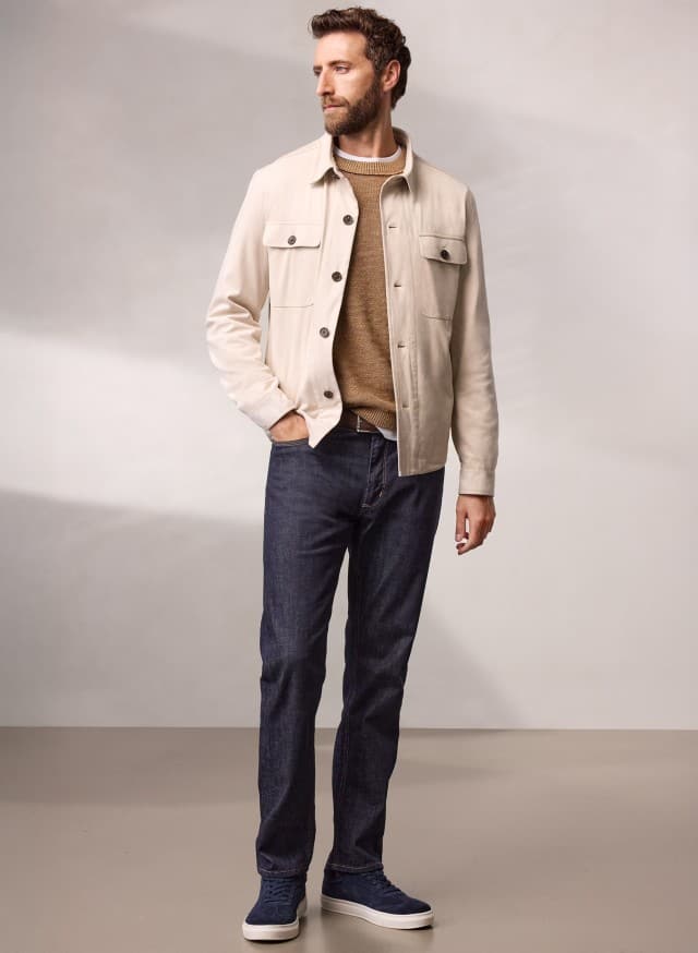 Ein Mann trägt eine Hemdjacke aus Microvelours in Beige, darunter einen Pullover in der Farbe Latte und dazu eine Jeans. Ein Mann trägt eine Hemdjacke aus Microvelours in Beige, darunter einen Pullover in der Farbe Latte und dazu eine Jeans.