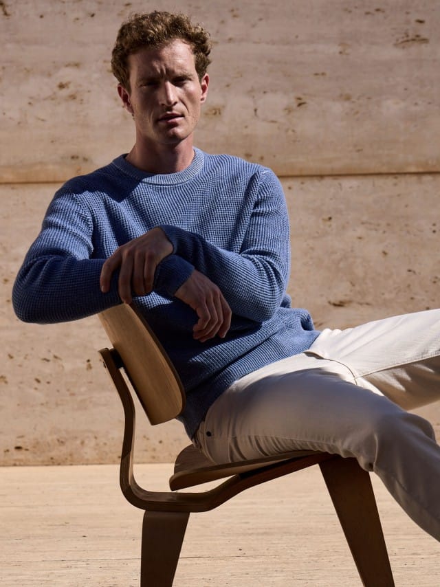 Ein Mann sitzt auf einem Stuhl vor einer Natursteinwand und trägt den Strukturpullover Bicolor in Jeansblau, dazu eine Jeans in Offwhite. Ein Mann sitzt auf einem Stuhl vor einer Natursteinwand und trägt den Strukturpullover Bicolor in Jeansblau, dazu eine Jeans in Offwhite.