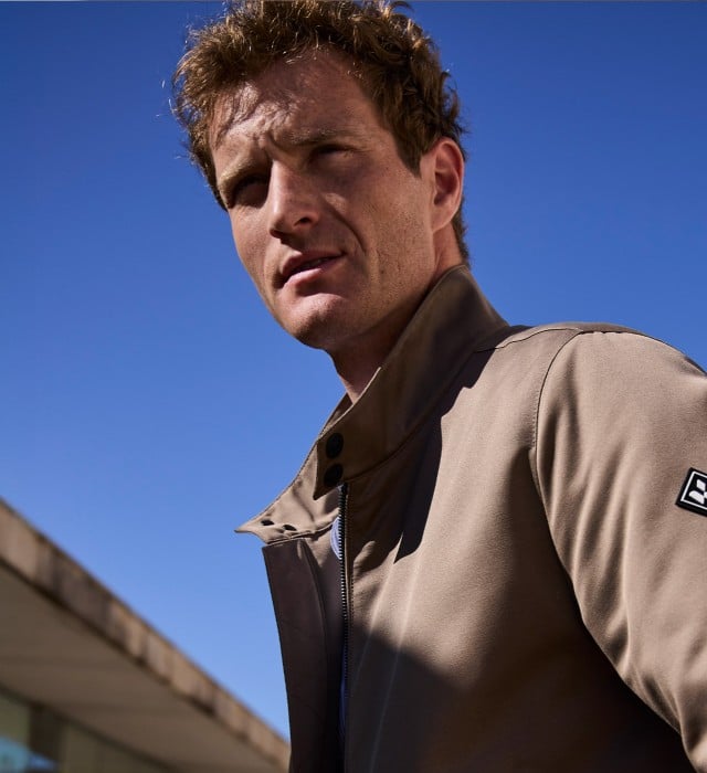 Ein Mann vor einem Natursteingebäude trägt einen graubraunen Freizeitblouson, dazu eine Jeans. Ein Mann vor einem Natursteingebäude trägt einen graubraunen Freizeitblouson, dazu eine Jeans.