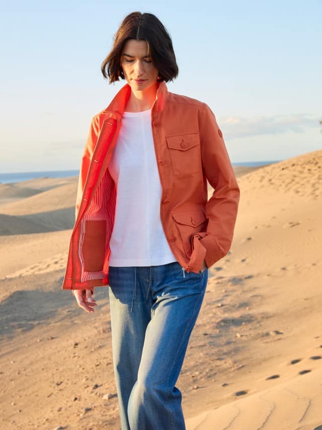 Eine Frau steht in den Dünen und trägt einen Jacke in Terra, darunter ein weißes Shirt und dazu eine Jeans. Eine Frau steht in den Dünen und trägt einen Jacke in Terra, darunter ein weißes Shirt und dazu eine Jeans.