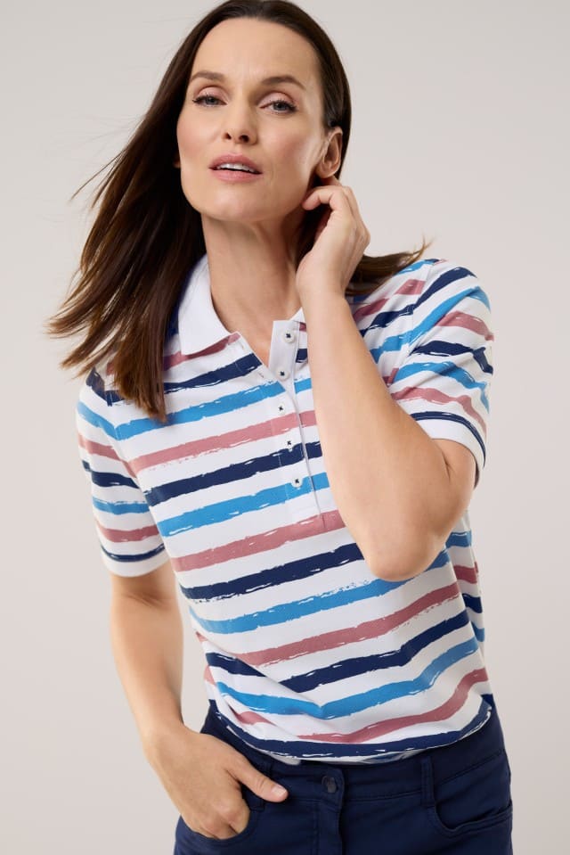 Eine Frau trägt Poloshirt Frischekick in Weiß gestreift, dazu eine Hose in Blau.