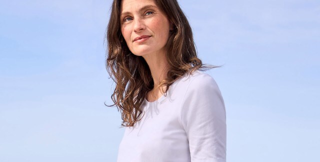Eine Frau trägt ein schlichtes, weißes T-Shirt. Das Outfit wirkt minimalistisch und zeitlos.