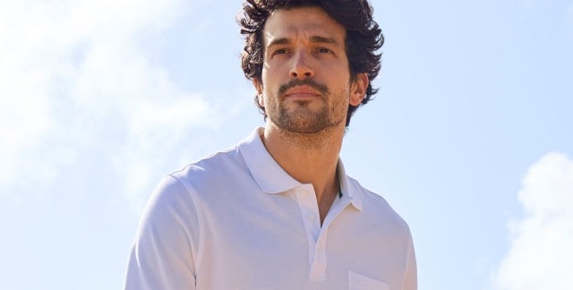 Ein Mann trägt ein weißes Polo-Shirt. 