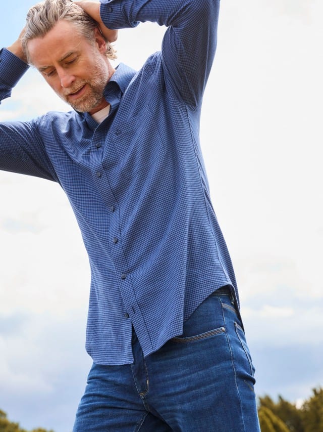Ein Mann trägt das Sturmtief Flanell-Hemd in Marine, darunter ein weißes Shirt und dazu eine blaue Jeans.