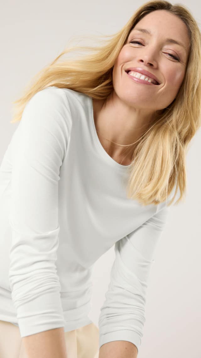 Eine blonde Frau trägt ein weißes Halbarm-Shirt.  