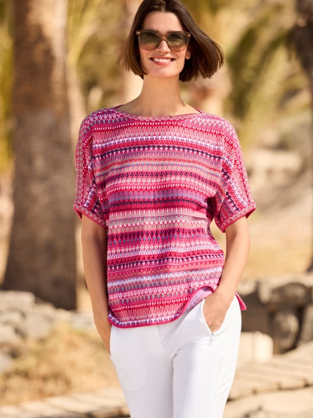 Frau mit Sonnenbrille trägt den Kimono-Pullover Baumwolljacquard dazu eine weiße Hose