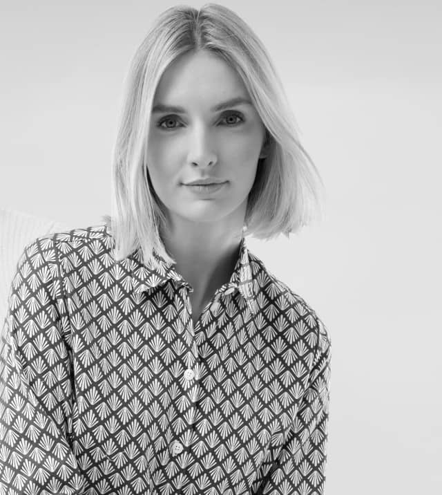 Ein Mann in einem weißen Strickpullover und eine Frau in einer gemusterten Bluse.