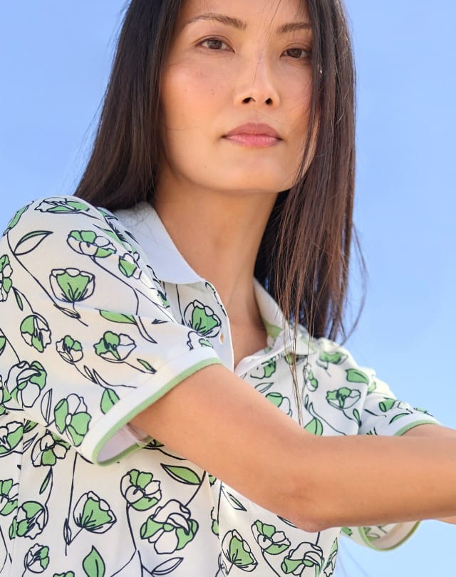 Eine Frau trägt ein Extraglatt Polo mit Blumenmuster in Salbei.