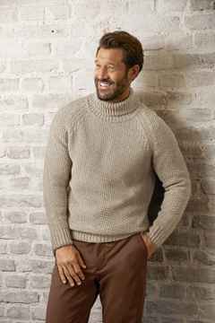 Ein Mann trägt einen Rollkragen-Pullover in Beige, dazu eine braune Hose.