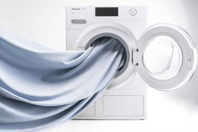 Geöffnete Waschmaschine mit einem hellblauen Stoff.