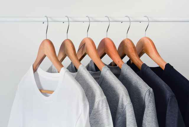 Kleiderstange mit mehreren Shirts jeweils auf einem Kleiderbügel.