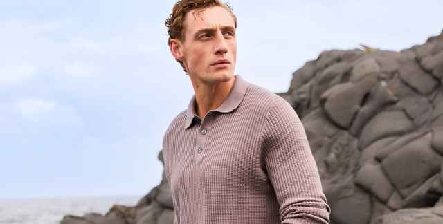Roséfarbener Strickpullover mit Polokragen, kurzer Knopfleiste und strukturierter Waffeloptik. Der Stil wirkt sportlich und hochwertig.