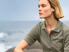 Person in einem olivgrauen Poloshirt mit klassischem Kragen und kurzen Ärmeln. Der Stil wirkt schlicht, lässig und zeitlos